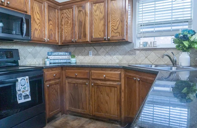 a kitchen with granite countertop wooden cabinets stainless steel appliances and a sink