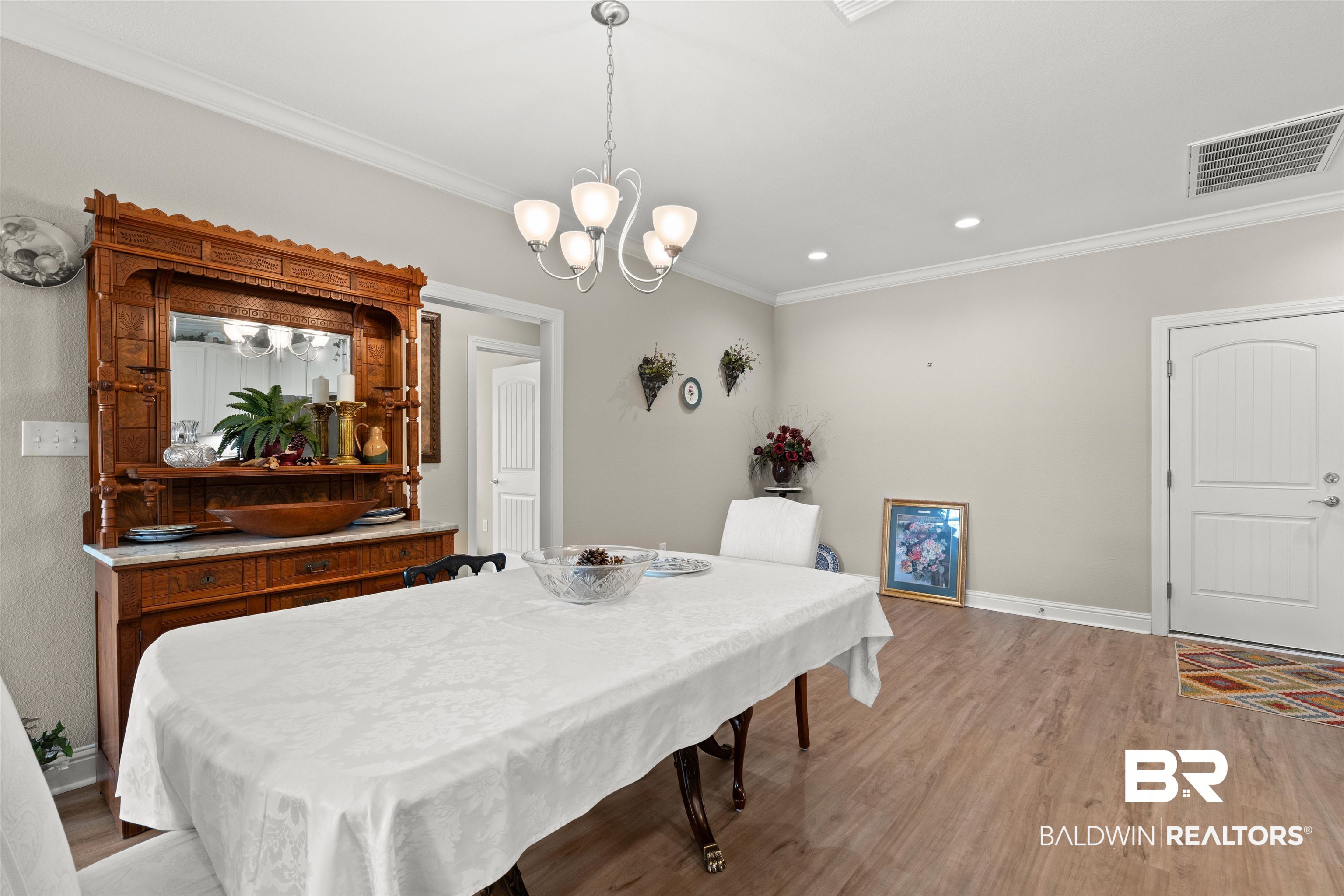 301 Holmes Avenue, Unit 301 Foley, AL 36535 - Photo 18 of 54 Dining space featuring light wood-type flooring, visible vents, a notable chandelier, ornamental molding, and baseboards