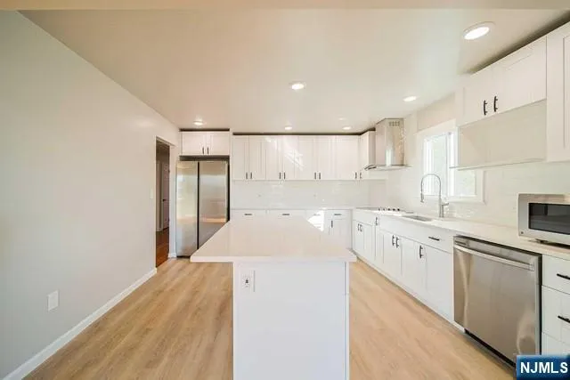 a kitchen with granite countertop a sink stainless steel appliances and white cabinets