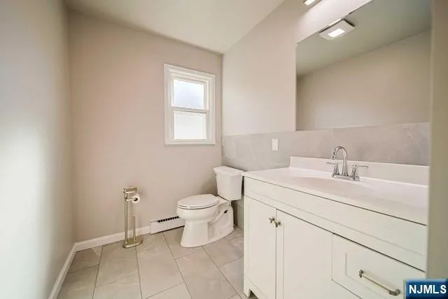 a bathroom with a toilet sink vanity and mirror