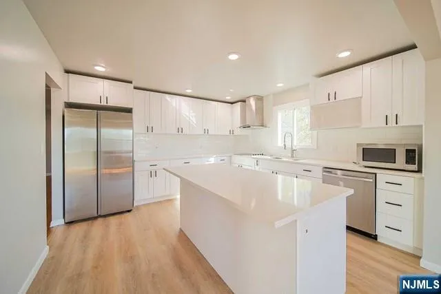 a large kitchen with stainless steel appliances kitchen island a large counter top and a refrigerator