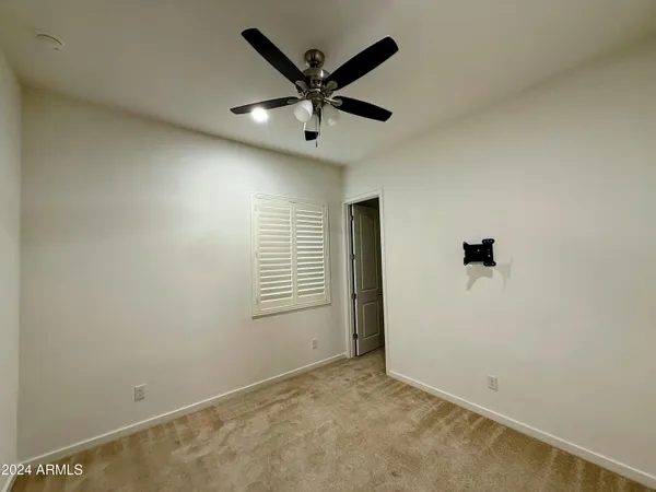 an empty room with ceiling fan and windows