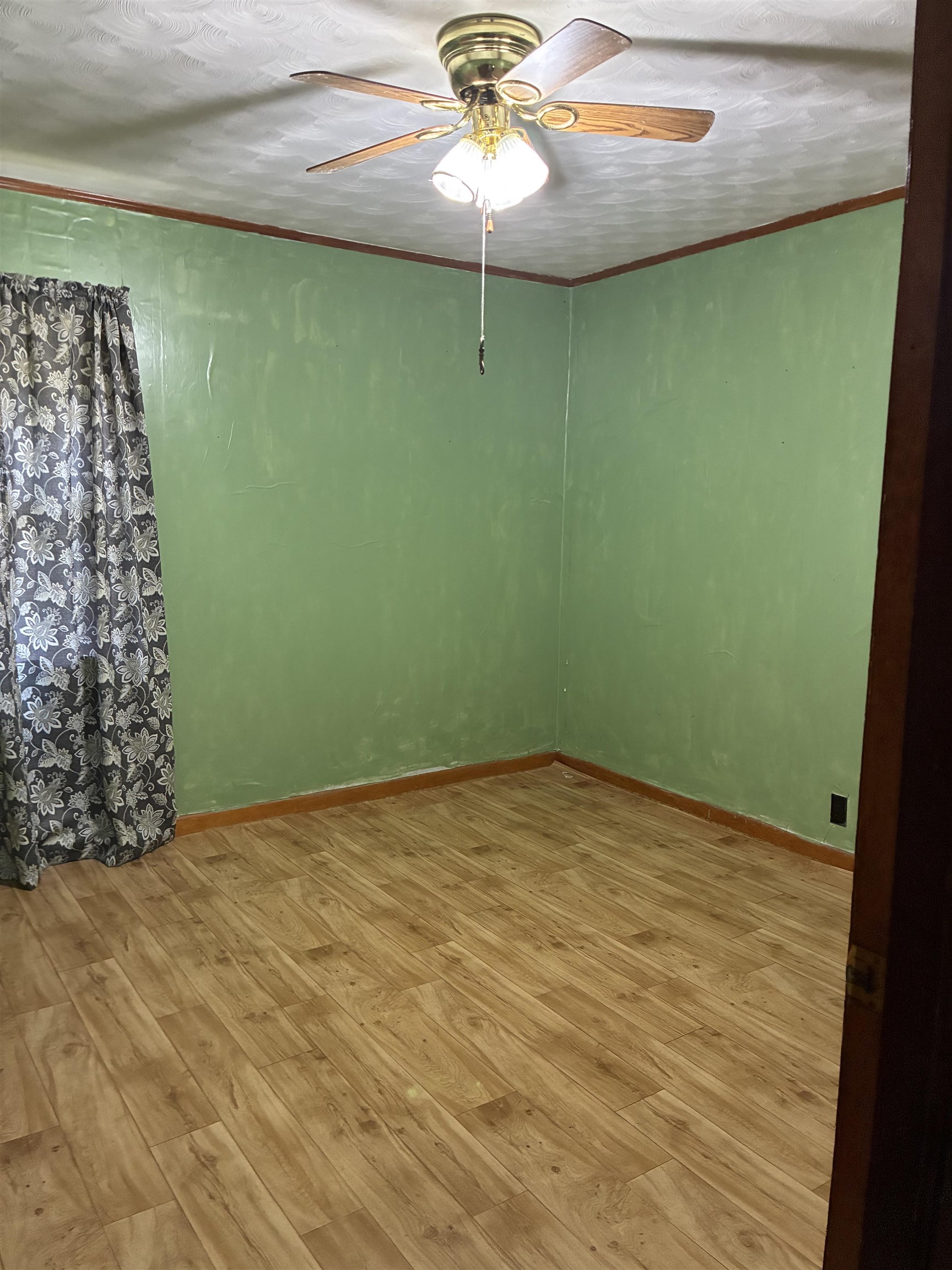 1421 Central Curve Road Ripley, TN 38063 - Photo 13 of 17 Spare room featuring light wood-style flooring, ceiling fan, crown molding, and a textured ceiling