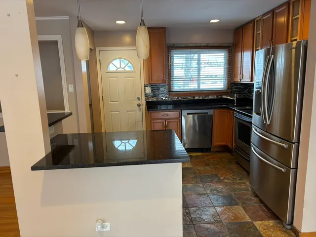 a kitchen with stainless steel appliances granite countertop a refrigerator a stove and a sink