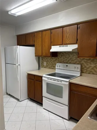 a kitchen with a stove top oven cabinets and a refrigerator