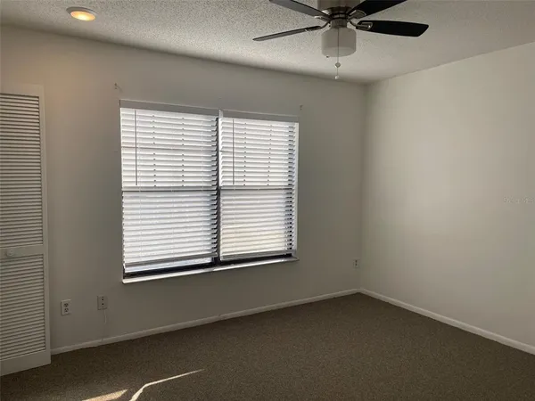 an empty room with a window and a fan