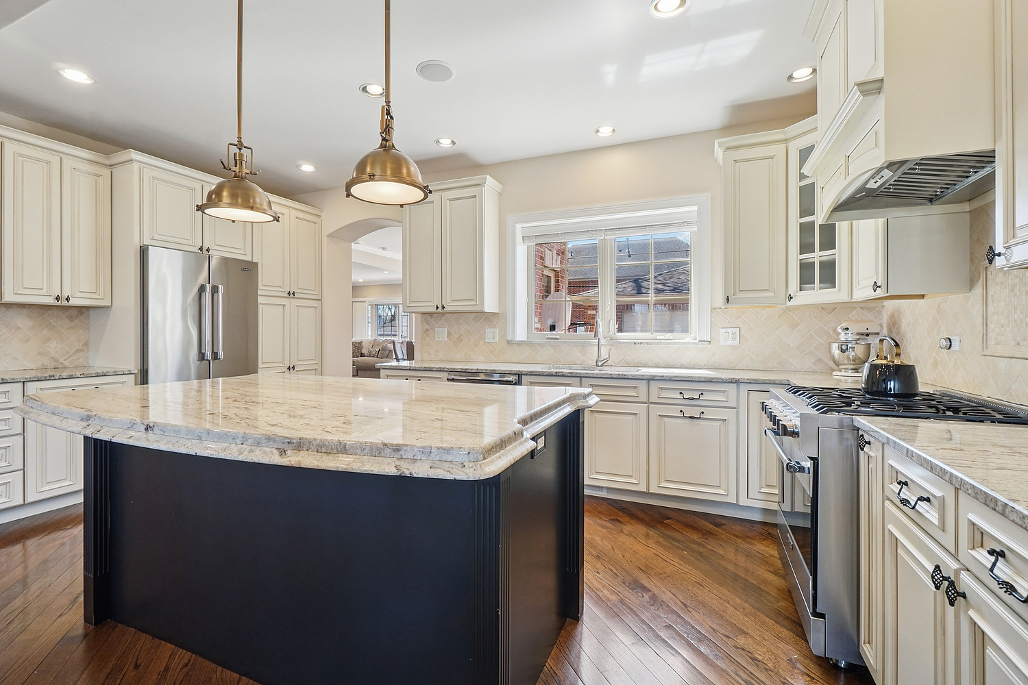 7039 Simpson Street Morton Grove, IL 60053 - Photo 7 of 24 a kitchen with stainless steel appliances granite countertop a sink a stove a refrigerator and island with wooden floor