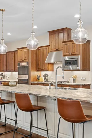 a kitchen with stainless steel appliances granite countertop a stove a sink dishwasher a dining table and chairs with wooden floor