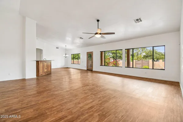 a view of an empty room with window and wooden floor