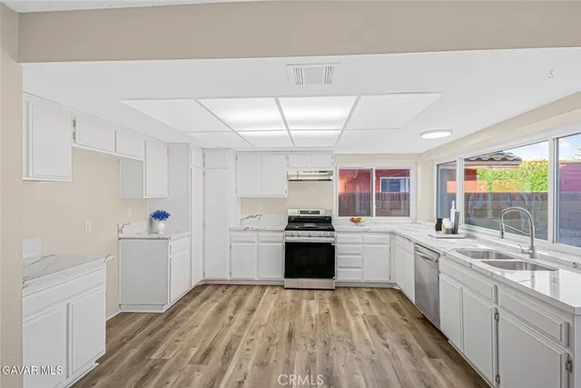 a kitchen with a sink a stove a refrigerator and white cabinets