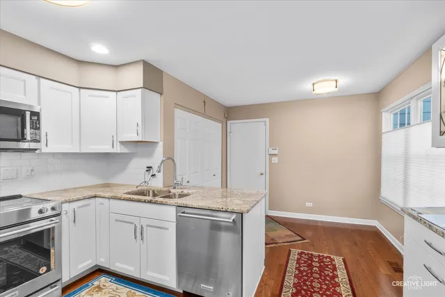 a kitchen with granite countertop white cabinets and white appliances