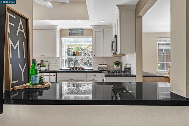 a kitchen with kitchen island granite countertop a sink a stove and a granite counter tops