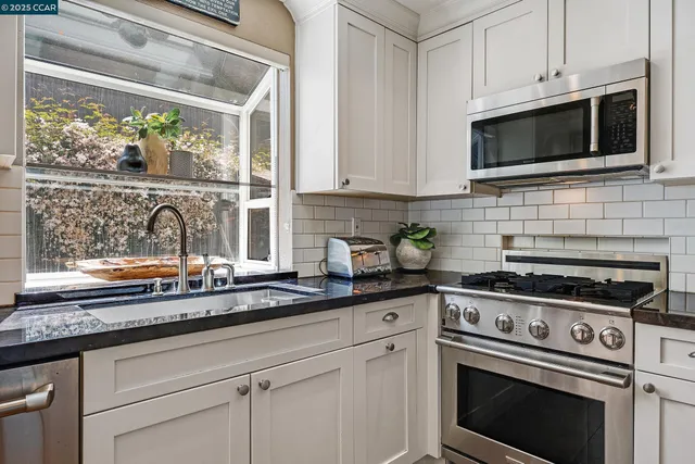 a kitchen with stainless steel appliances white cabinets and a stove top oven