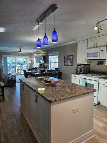 a kitchen with stainless steel appliances granite countertop a sink dishwasher and white cabinets with wooden floor