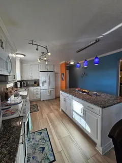 a large kitchen with granite countertop a lot of cabinets a sink and a stove