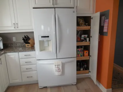 a kitchen with white cabinets and refrigerator