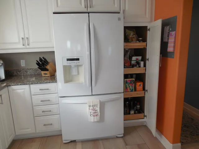 a kitchen with white cabinets and refrigerator