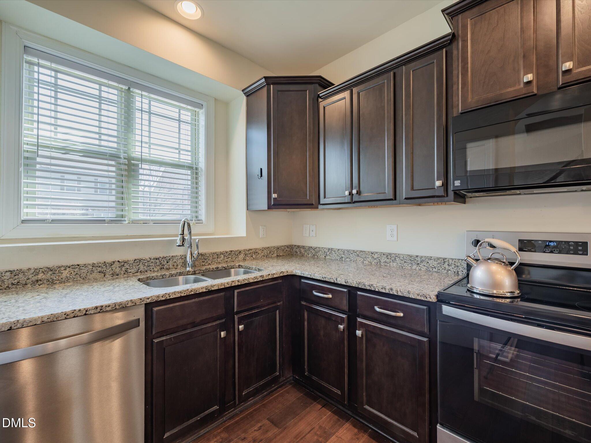 2808 Piedmont River Way Raleigh, NC 27606 - Photo 5 of 28 a kitchen with granite countertop stainless steel appliances a sink window and cabinets