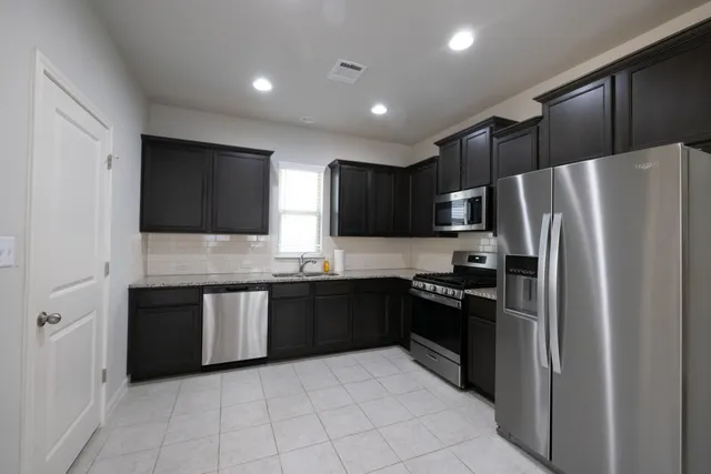 a large kitchen with granite countertop a refrigerator and a sink