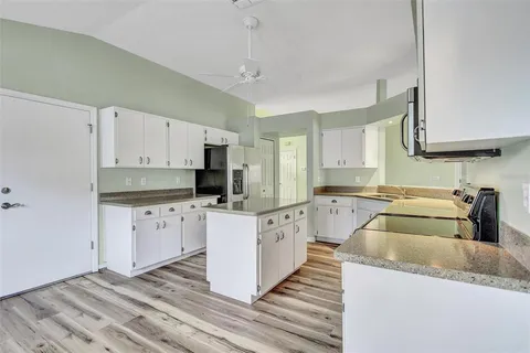 a kitchen with granite countertop a sink a counter top space stainless steel appliances and cabinets