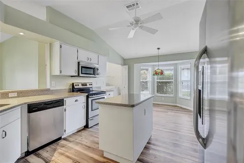 a kitchen with stainless steel appliances white cabinets a sink a stove a refrigerator and white cabinets