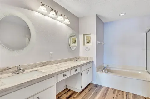a bathroom with a granite countertop bathtub sink vanity and mirror