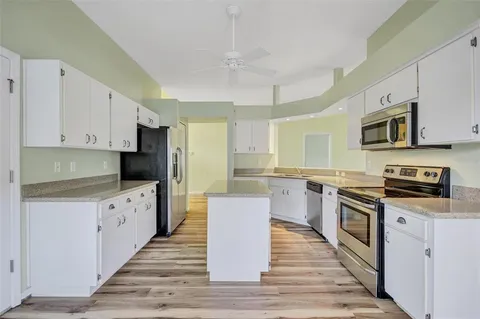 a large kitchen with stainless steel appliances granite countertop a stove top oven a sink dishwasher and a refrigerator