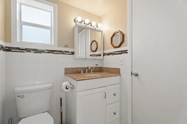 a bathroom with a granite countertop toilet sink and mirror