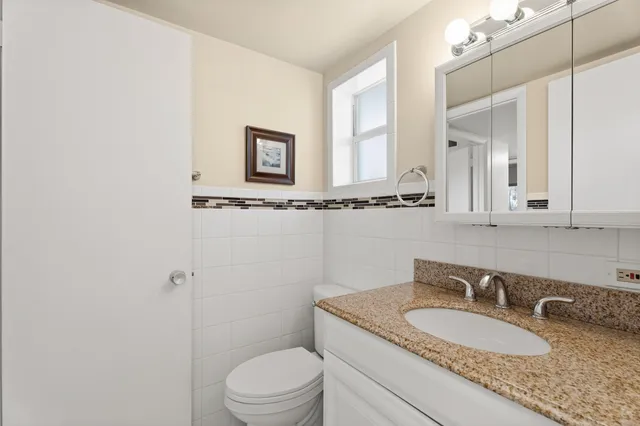 a bathroom with a granite countertop sink mirror vanity and toilet