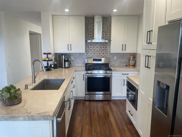 a kitchen with a sink dishwasher a refrigerator and a stove with wooden floor