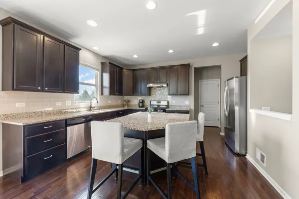 a kitchen with a table chairs refrigerator microwave and cabinets