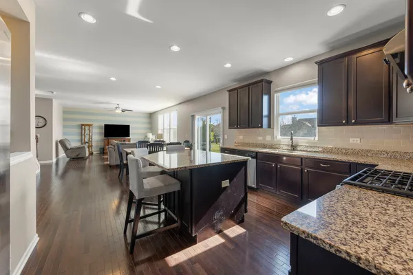 a kitchen with stainless steel appliances granite countertop table chairs sink and cabinets