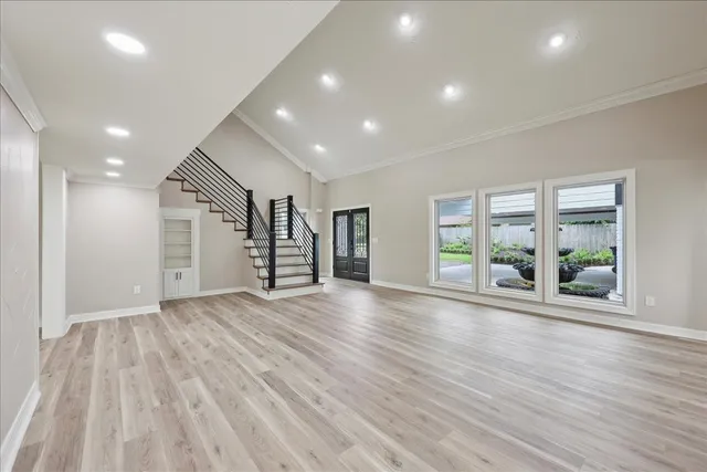 an empty room with wooden floor and windows