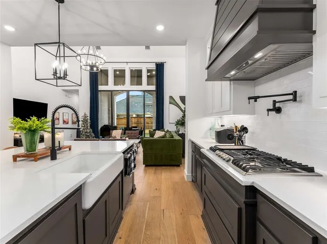 a kitchen with granite countertop a sink dishwasher a microwave oven a stove with chairs and wooden floor