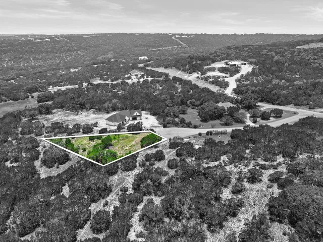 an aerial view of residential houses with outdoor space and trees