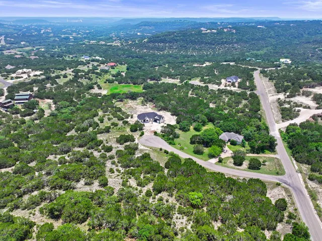 an aerial view of residential houses with outdoor space and trees