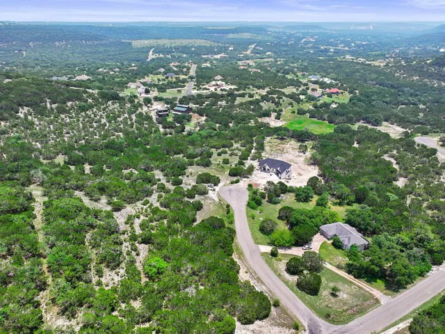 an aerial view of residential houses with outdoor space and trees