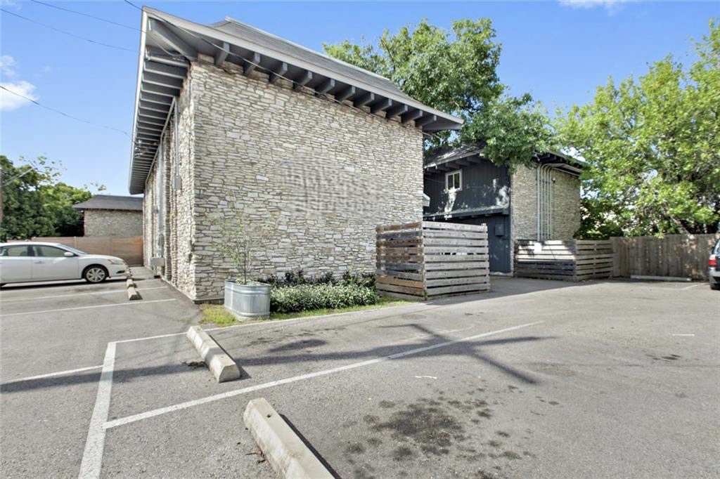 2301 Ohlen Road, Unit 107 Austin, TX 78757 - Photo 2 of 8 View of home's exterior with stone siding and uncovered parking
