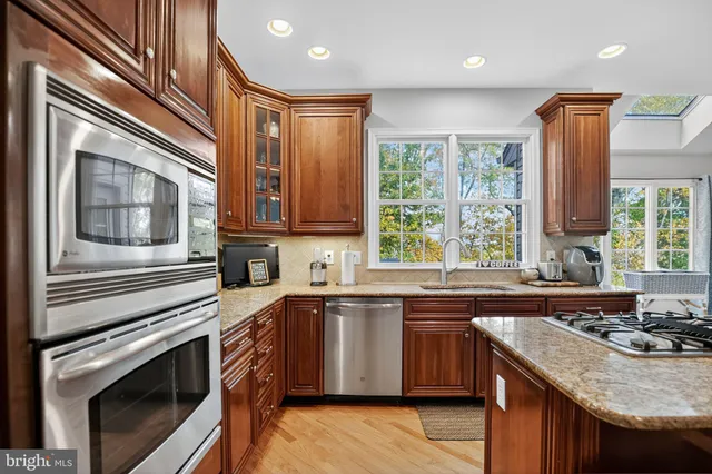 a kitchen with stainless steel appliances granite countertop a sink a stove a microwave cabinet and refrigerator