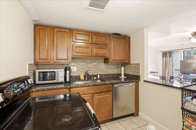 1334 Ridgewood Lane Bountiful, UT 84010 - Photo 29 of 38 Kitchen featuring wood cabinetry, a mosaic tile backsplash, a stainless steel dishwasher, and a granite-style countertop