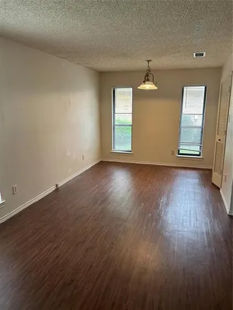 an empty room with wooden floor windows and cabinet