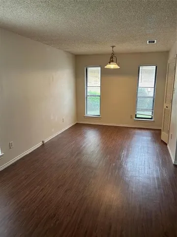 an empty room with wooden floor windows and cabinet