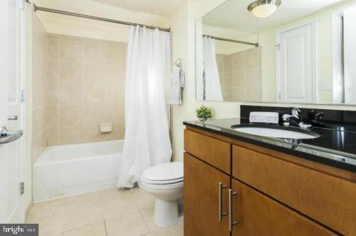 915 E Street Northwest, Unit 714 Washington, DC 20004 - Photo 11 of 14 a bathroom with a granite countertop sink a toilet and shower