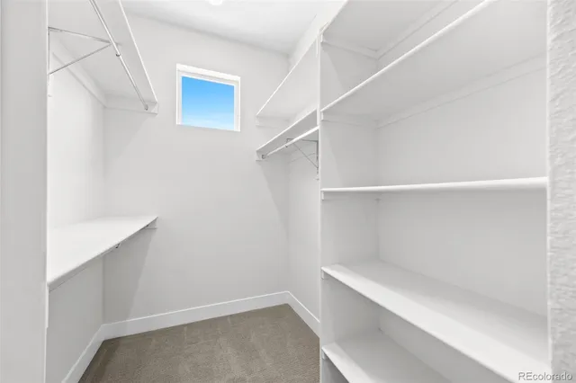 an empty room with chandelier fan and windows