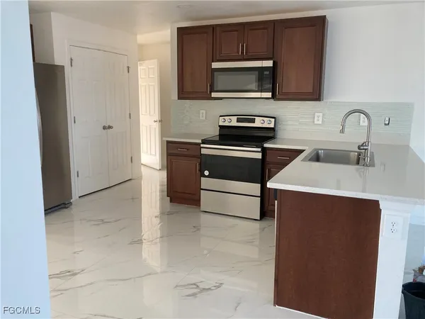 a kitchen with stainless steel appliances a stove microwave and sink