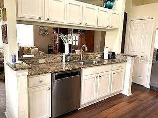 a kitchen with stainless steel appliances granite countertop a sink and cabinets with wooden floor