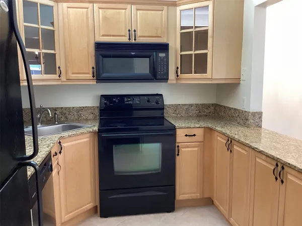 a kitchen with granite countertop white cabinets stainless steel appliances and a sink