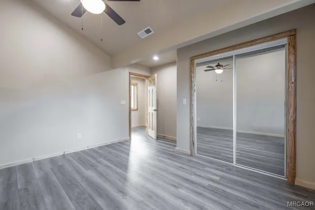 a view of an empty room with a window and wooden floor