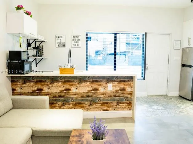 a large white kitchen with a stove a sink dishwasher and a refrigerator with wooden floor