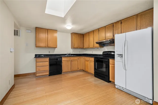 a kitchen with granite countertop a refrigerator stove top oven and sink